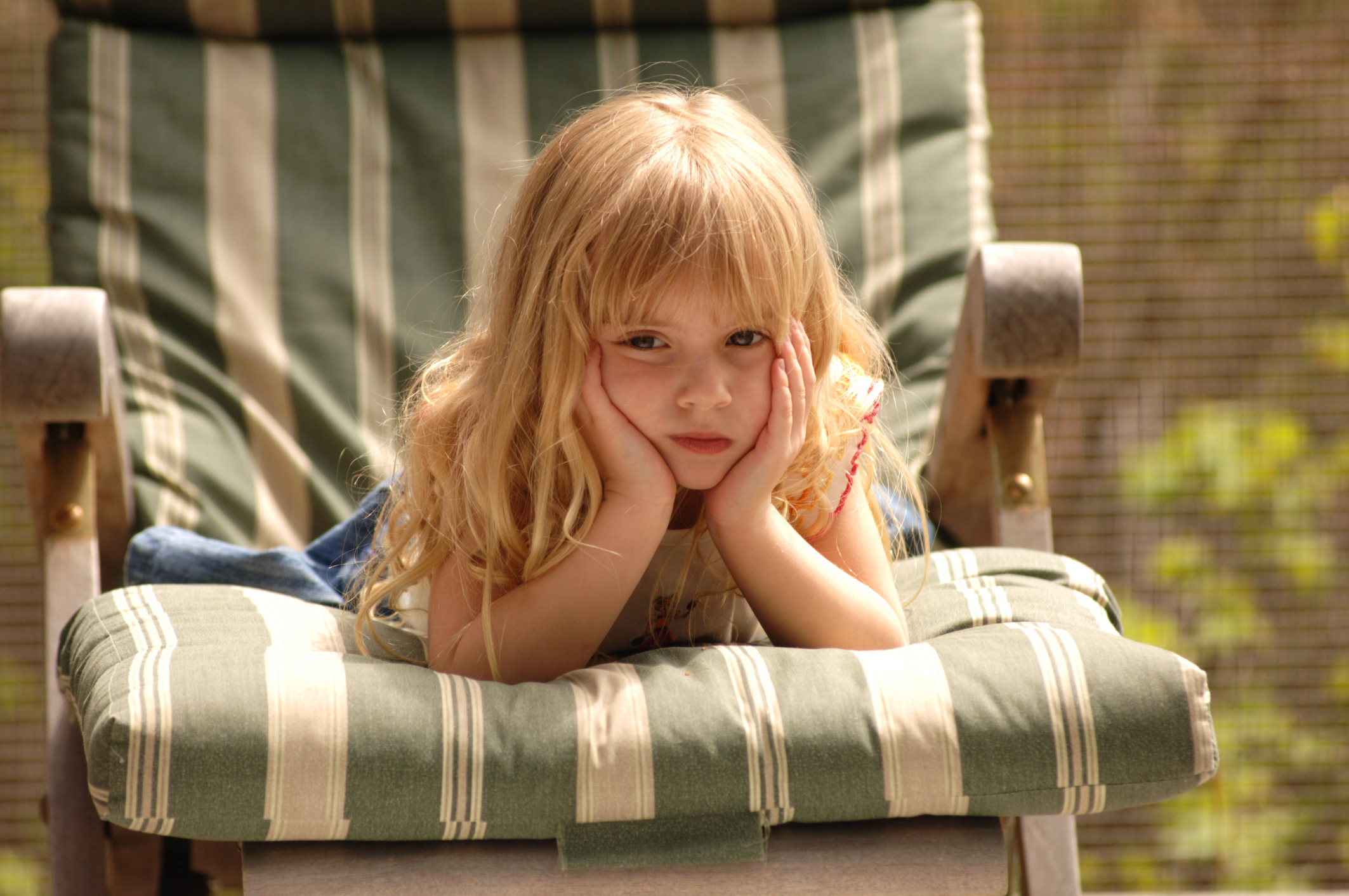 Blond girl on chair with her hands to her face
